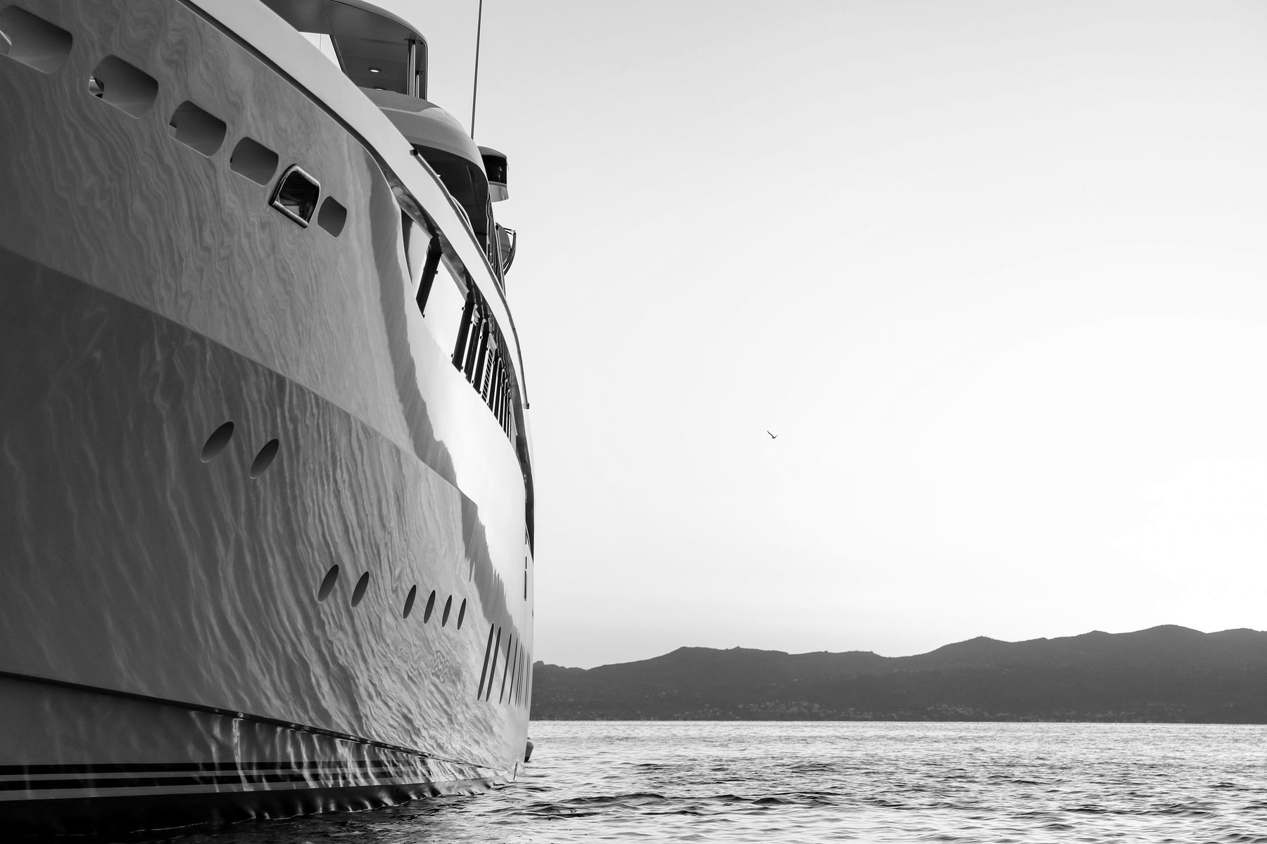 The bow of a superyacht catching golden light at sunset