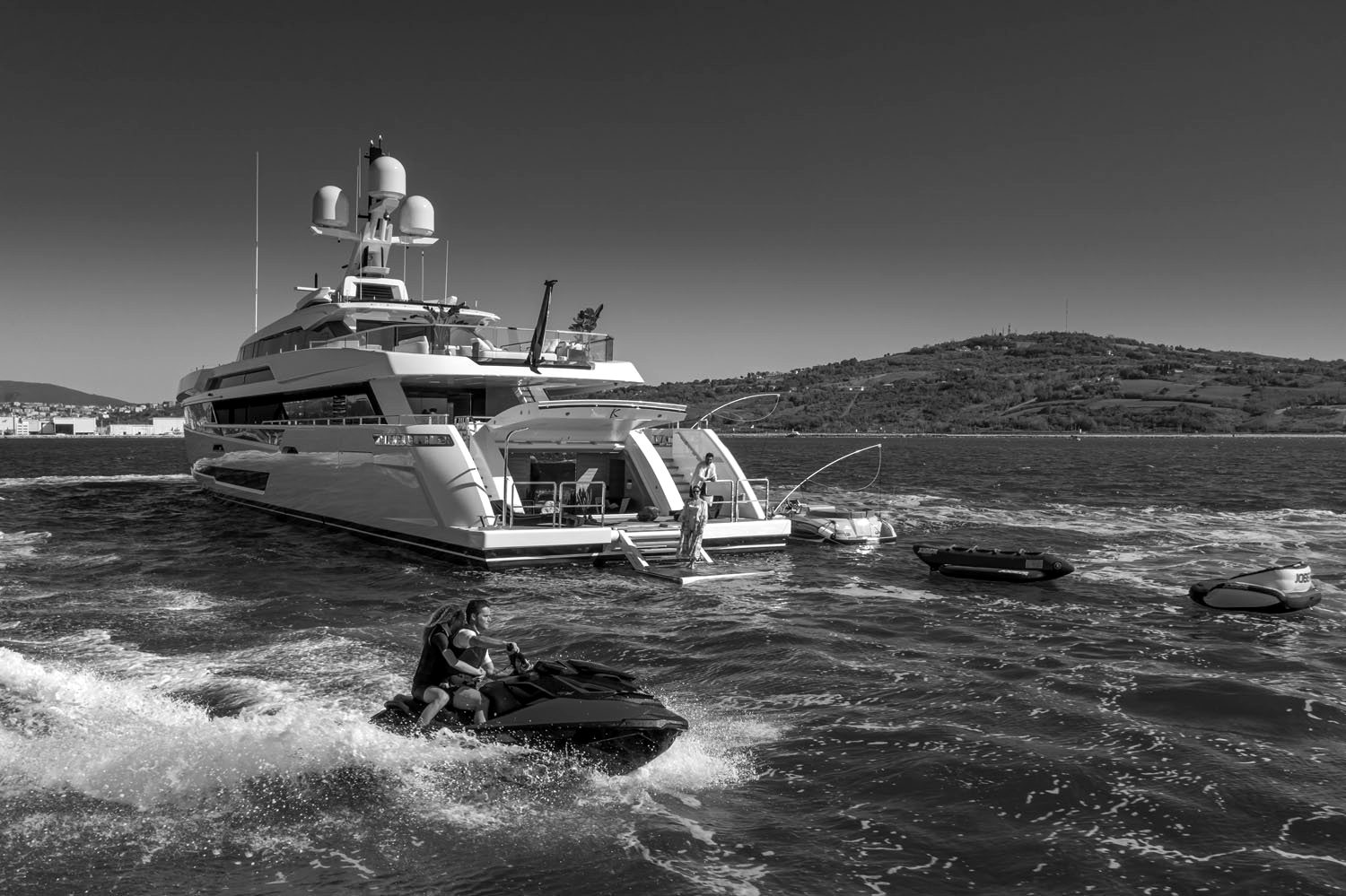 Guests on jet skis and water toys beside a superyacht at anchor