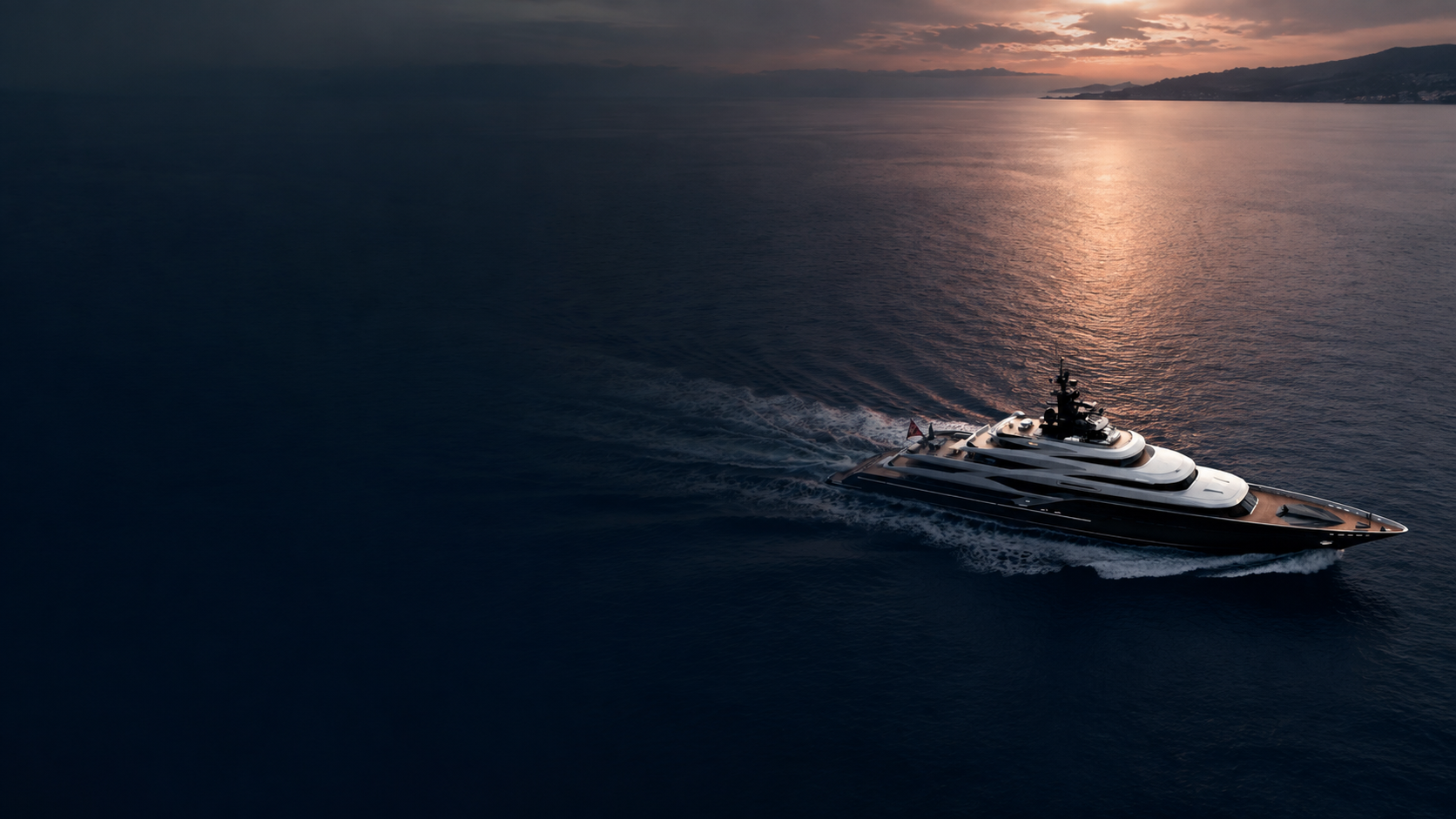 A superyacht under way at sunset on a calm, dark sea