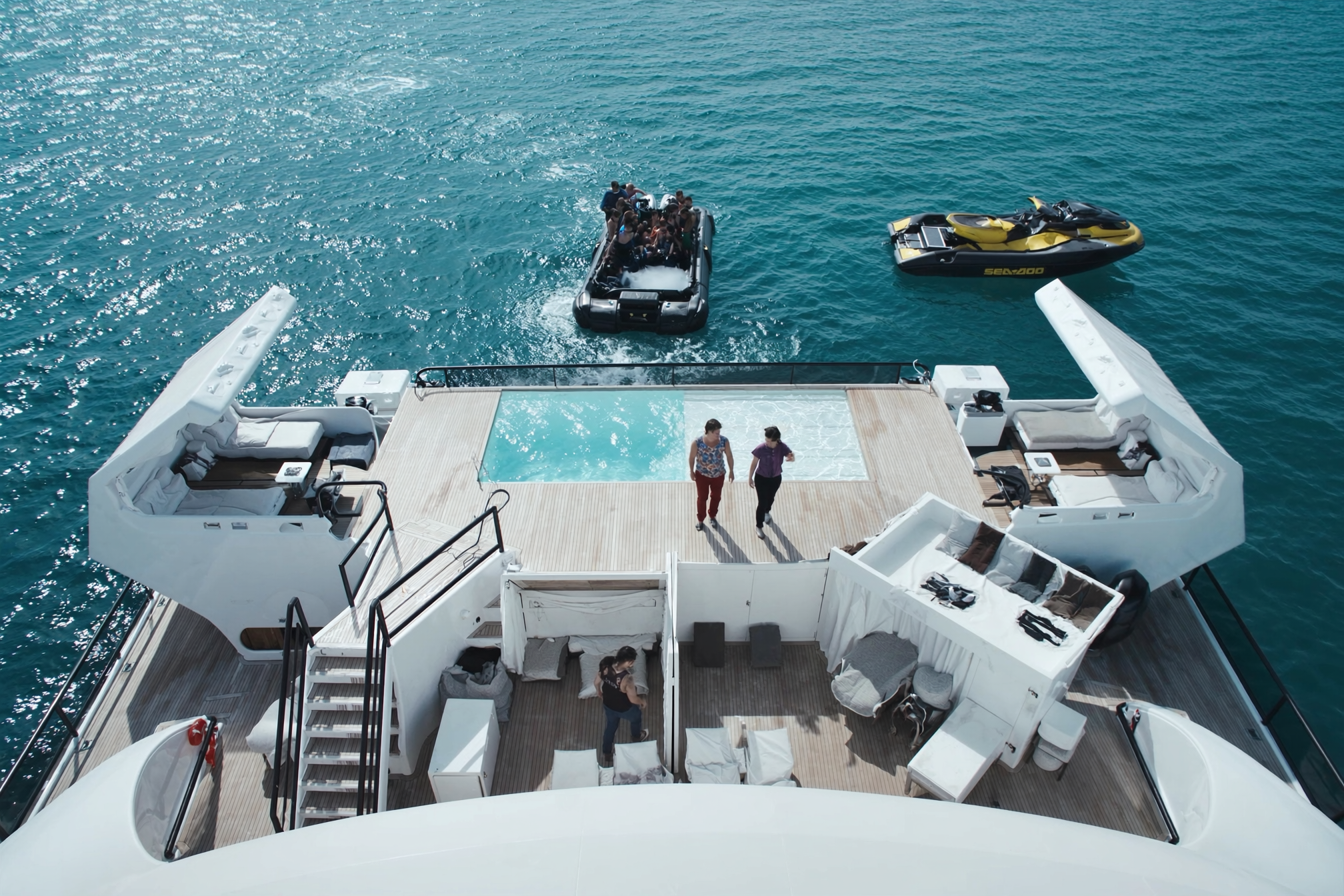 Aerial view of a superyacht beach club, pool and tenders at anchor