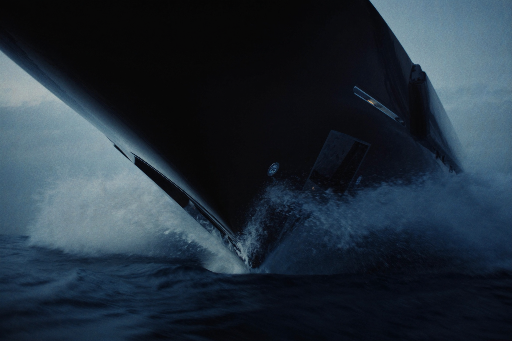A superyacht bow cutting through deep blue water