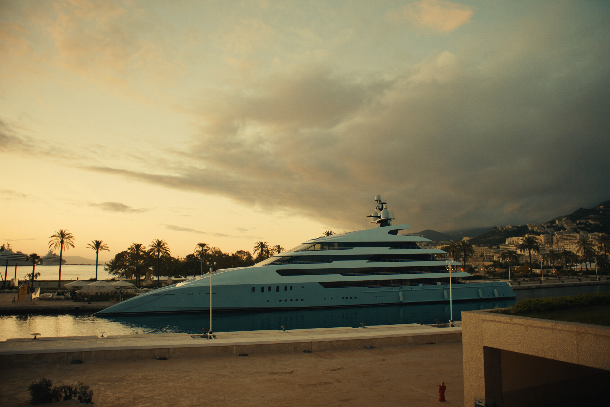 A superyacht berthed in a Mediterranean harbour at golden hour