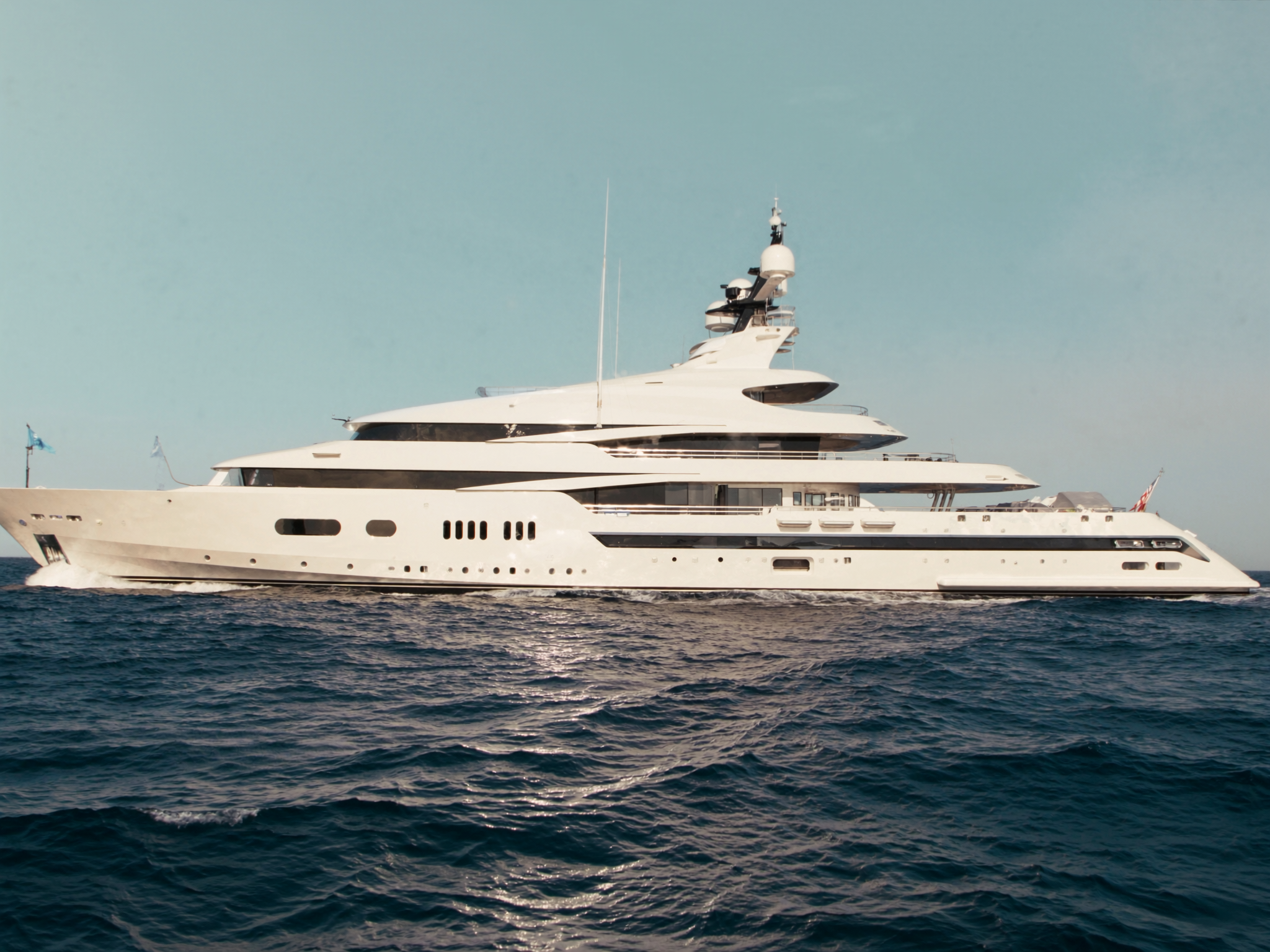 A sleek modern white motor superyacht under way on open blue sea